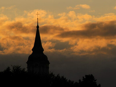 Kirchturm Stadtpfarrkirche Sankt Barbara mit Sonnenuntergang im Hintergrund